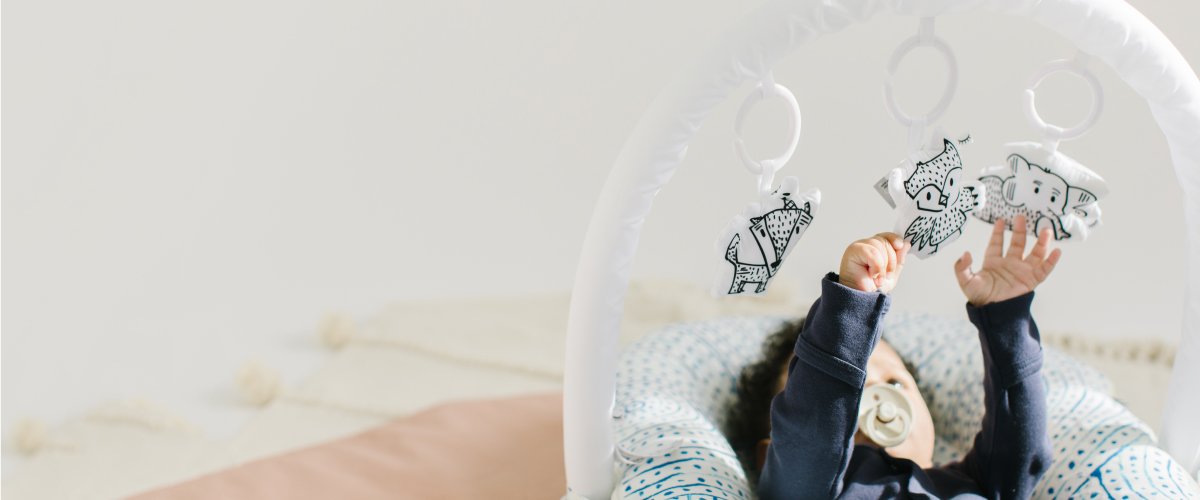 baby plays with sleepyhead toy arch